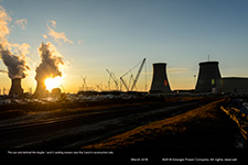 The sun sets behind the Vogtle 1 and 2 cooling towers near the 3 and 4 construction site.