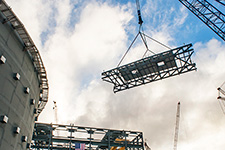 The heavy lift derrick guides the final roof truss toward the Unit 3 turbine building.