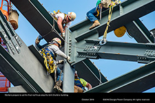 Workers prepare to set the final roof truss atop the Unit 3 turbine building.